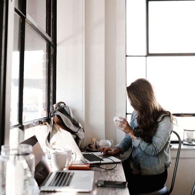 Woman in Gray Jacket Sitting Beside Desk